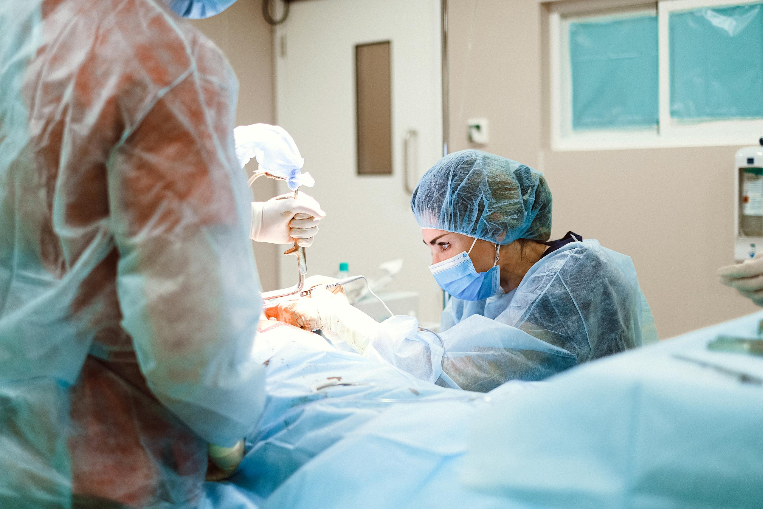 Female surgeon performing a surgical procedure in an operating room with sterile equipment.